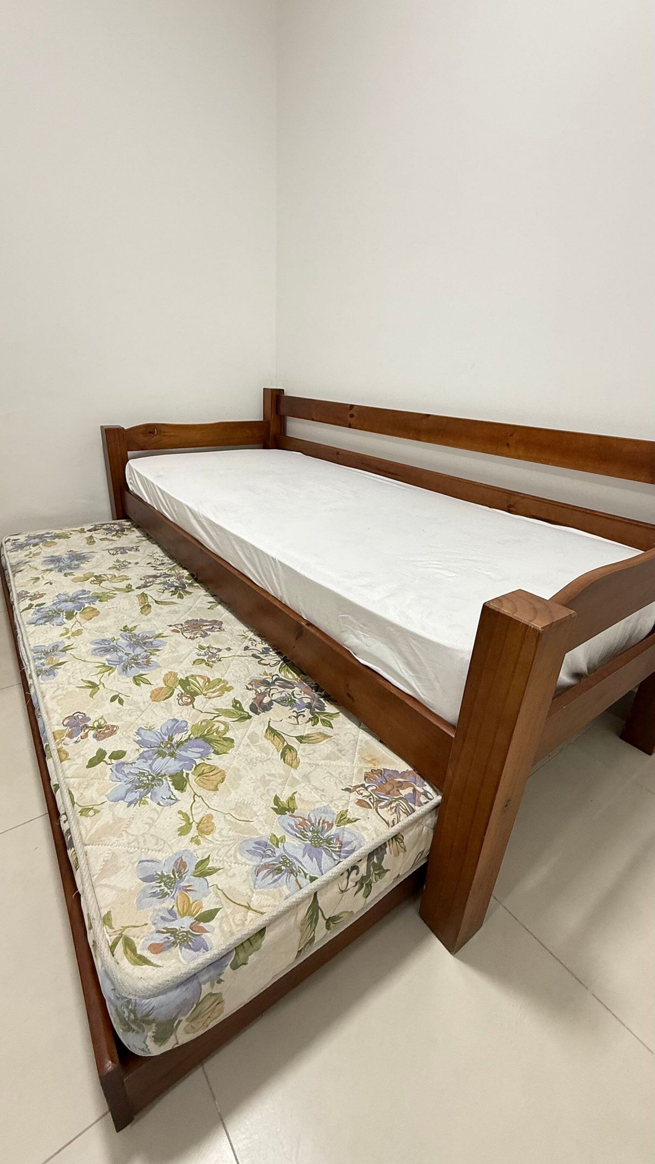 A single bed with a wooden frame and a mattress with a floral pattern.