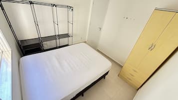 Un dormitorio con cama, armario y estantería metálica.
