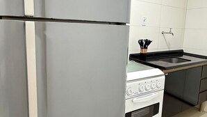 Una cocina con un refrigerador gris, una estufa y un lavamanos.