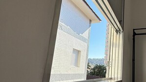 Una ventana con vista a un edificio de fachada con tejas y un balcón.