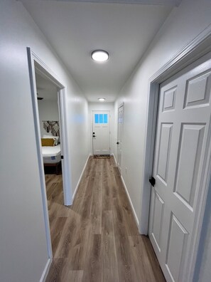 A hallway with wooden flooring, white walls, and doors on both sides. - Lake My Day – Relaxing Cottage Getaway at Canadohta Lake (Union City)