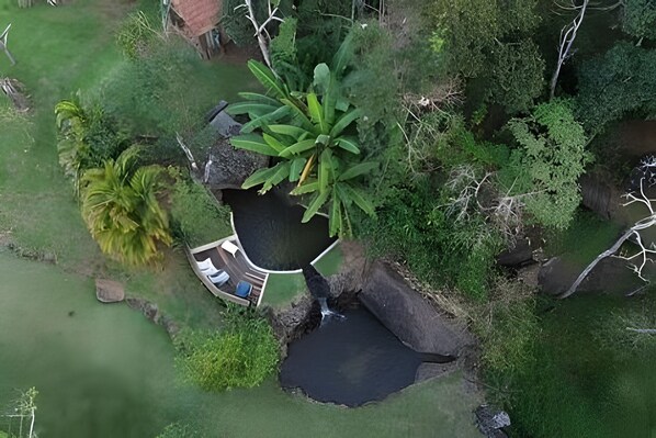 An aerial view of a landscaped area with a pond, a small waterfall, and a seating area with a table and chairs. - Vida na Roça (São Bento do Sapucaí)