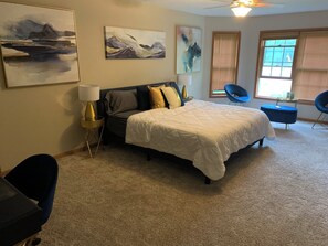 A bedroom with a bed, two chairs, a lamp, and artwork on the walls. - Spacious 6-bedroom house with AC in soothing POCONO MOUNTAINS (Saylorsburg)