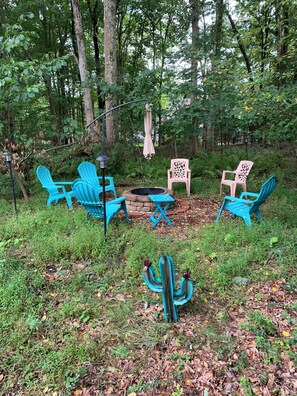 An outdoor seating area with blue chairs and a table, surrounded by trees and a cactus. - Spacious 6-bedroom house with AC in soothing POCONO MOUNTAINS (Saylorsburg)