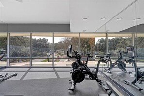 A modern gym with stationary bikes and a large window overlooking a park. - Elevated 1 Bedroom Corner (Orlando)