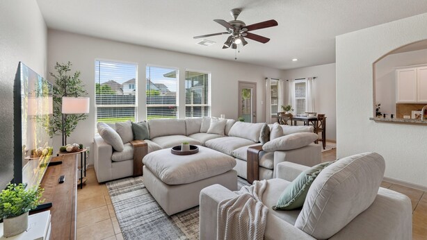A modern living room with a sectional sofa, a dining area, and a ceiling fan. - The Olive House - Stylish 4BR Retreat - Sleeps 10 - Newly Furnished (Tomball)