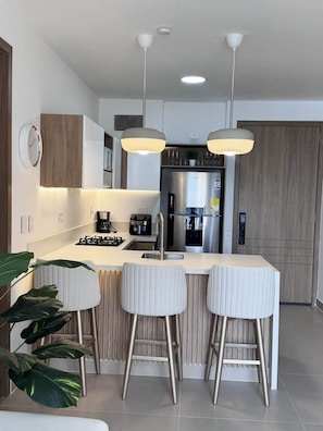 A modern kitchen with a central island, stainless steel appliances, pendant lighting, and a clock on the wall. - Exclusive, Panoramic Terrace, and Dreamlike Views (Cartagena Province)