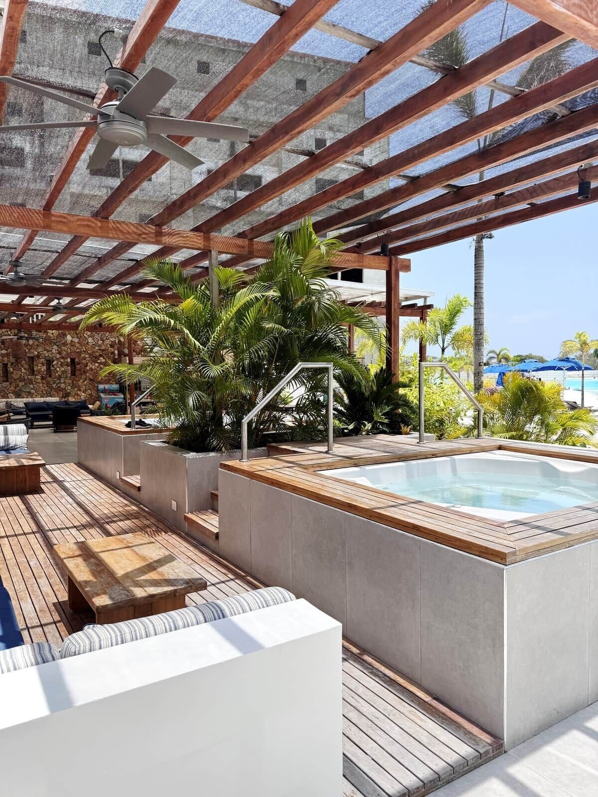 Un espace piscine sur le toit, comprenant un jacuzzi, une terrasse en bois et des sièges extérieurs.