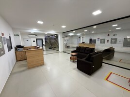 Una moderna zona de recepción con mostrador, área de estar y una escalera que lleva a un piso superior.