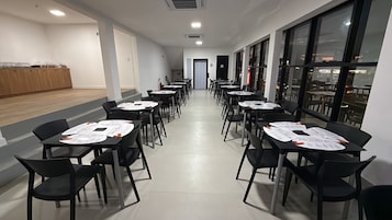 Un salón de conferencias con mesas, sillas, una barra de madera y ventanas amplias.