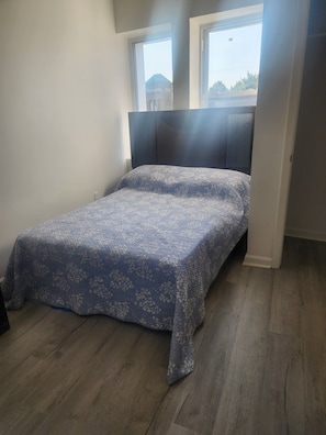 A single bed with a floral bedspread in a room with wooden flooring and a window. - Fantastic 2-bedroom apartment with AC in Drexel Hill (Drexel Hill)
