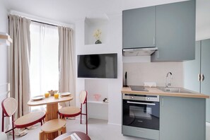 Eine moderne Küche mit grauen Schränken, einem eingebauten Backofen und einem Flachbildfernseher.