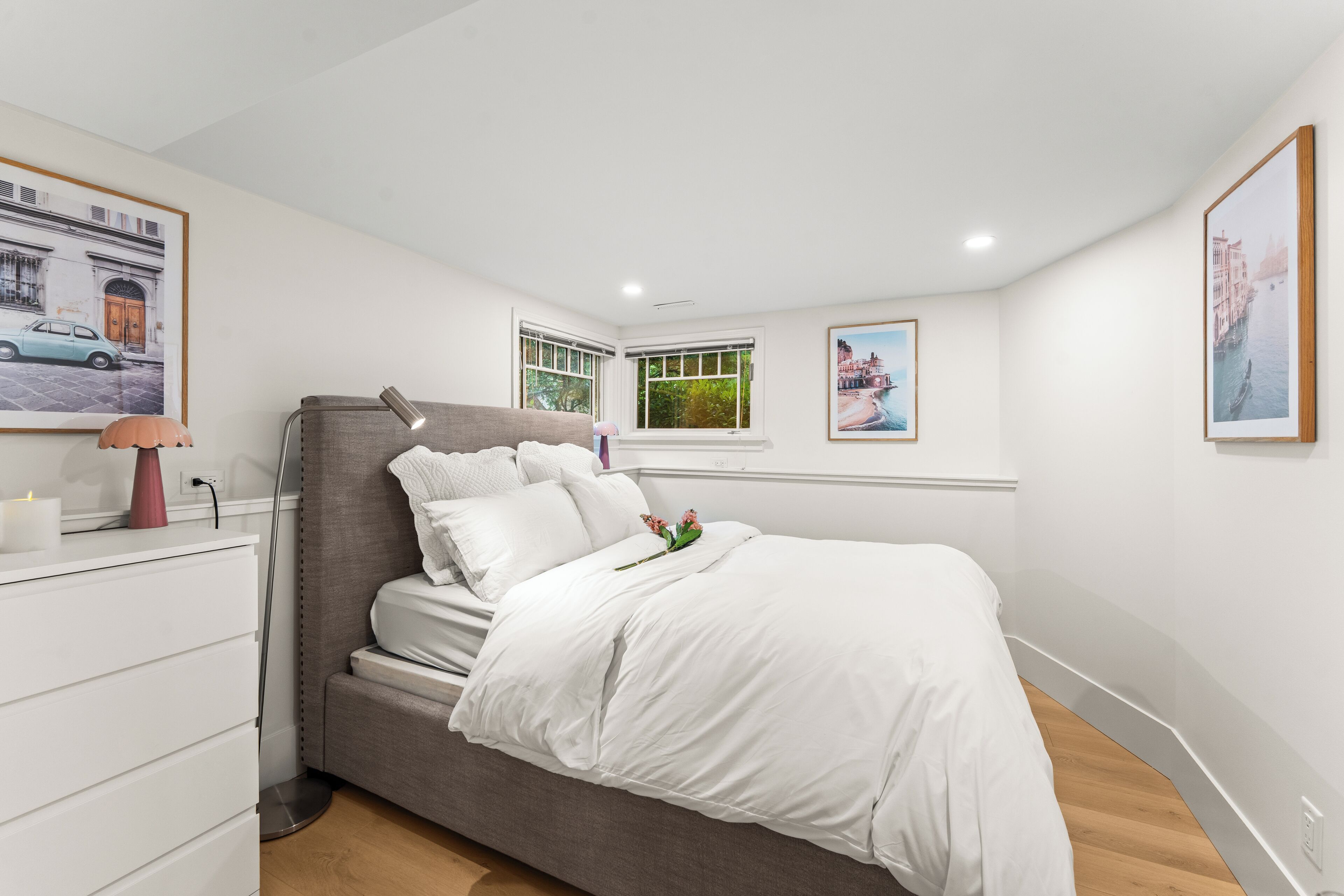 Een slaapkamer met een bed, nachtkastje, lamp en raam.