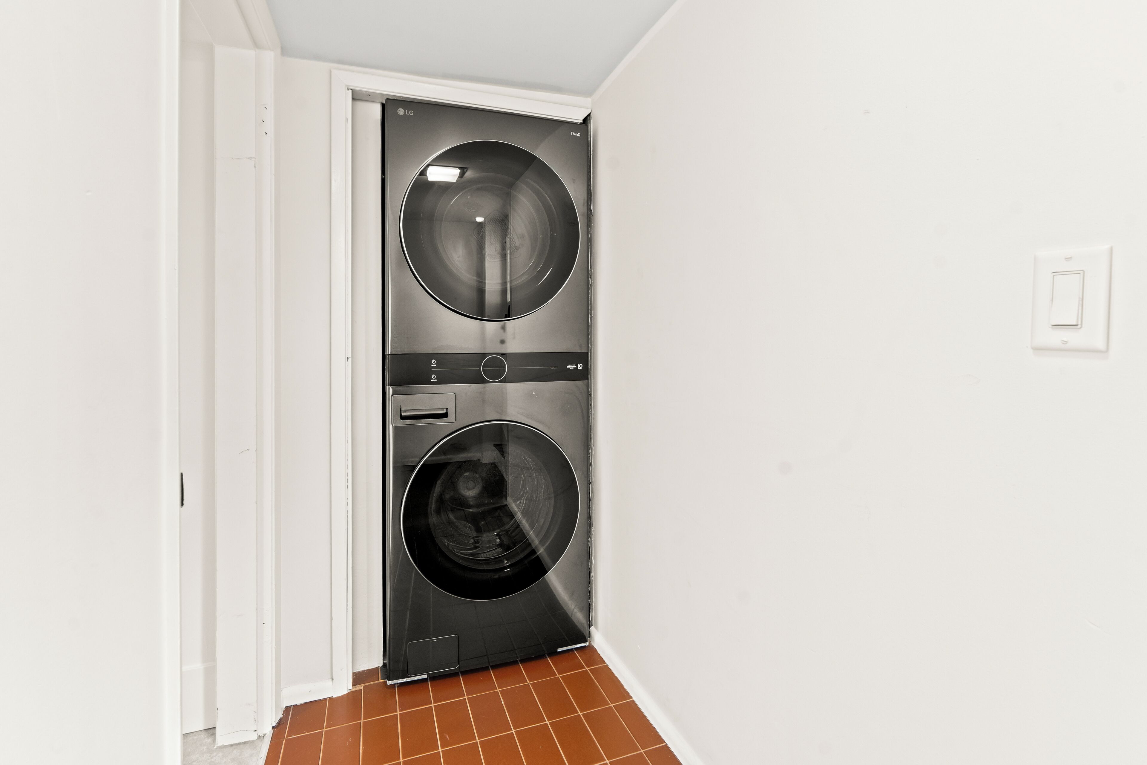 A laundry room with two front-loading washing machines and a door leading to another room.