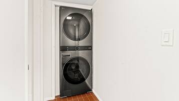 A laundry room with two front-loading washing machines and a door leading to another room.