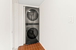 Un cuarto de lavado con dos lavadoras de carga frontal y una puerta que da a otra habitación.