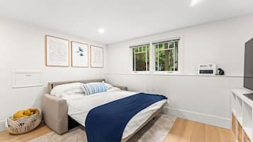 A bedroom with a bed, a window, a wall-mounted WiFi sign, and framed artwork.