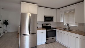 A modern kitchen with stainless steel appliances, white cabinetry, and a light wood floor. - Modern Home • Walk to Design Dist• Free Parking (Miami)