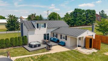 A two-story house with a patio, hot tub, and outdoor seating area.