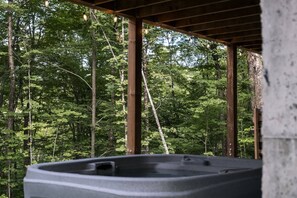 Ein Whirlpool unter einer Holzkonstruktion mit Blick auf den Wald.