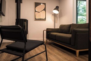 Ein modernes Wohnzimmer mit einer Couch, einem Sessel, einer Stehlampe und einem Kamin.