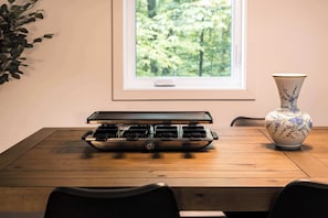 A kitchen with a stove, a window with a view of greenery, and a decorative vase. - Spa, Comfort & Escape | ASKA (Saint-Côme)