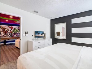 Ein Schlafzimmer mit einem Bett, einem Schminktisch, einem Spiegel und einem Wandbild.