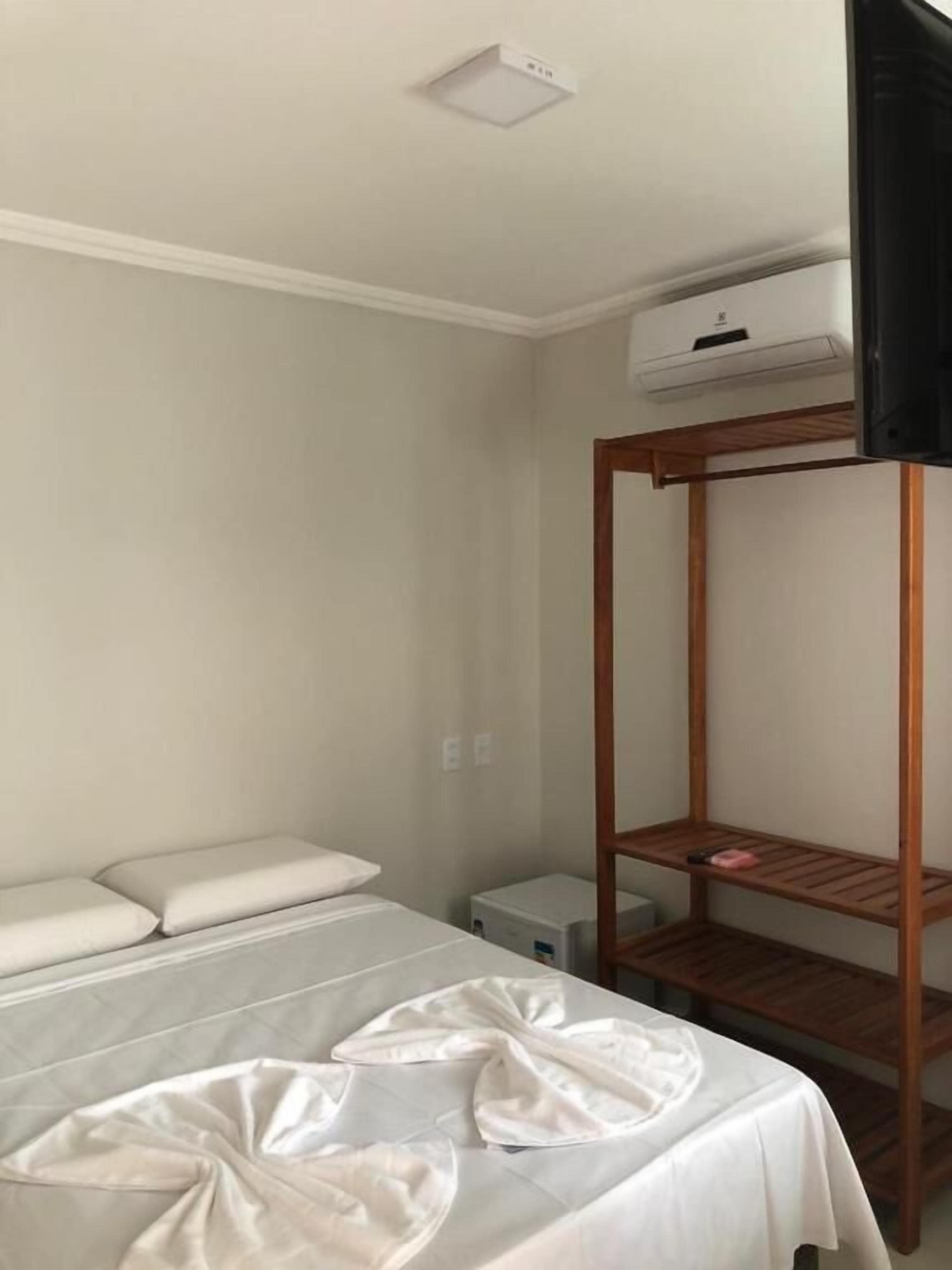 A room with a bunk bed, a bedside table, and a wall-mounted air conditioning unit.