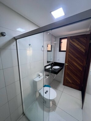 Een moderne badkamer met een douchecabine van glas, toilet en wastafel.