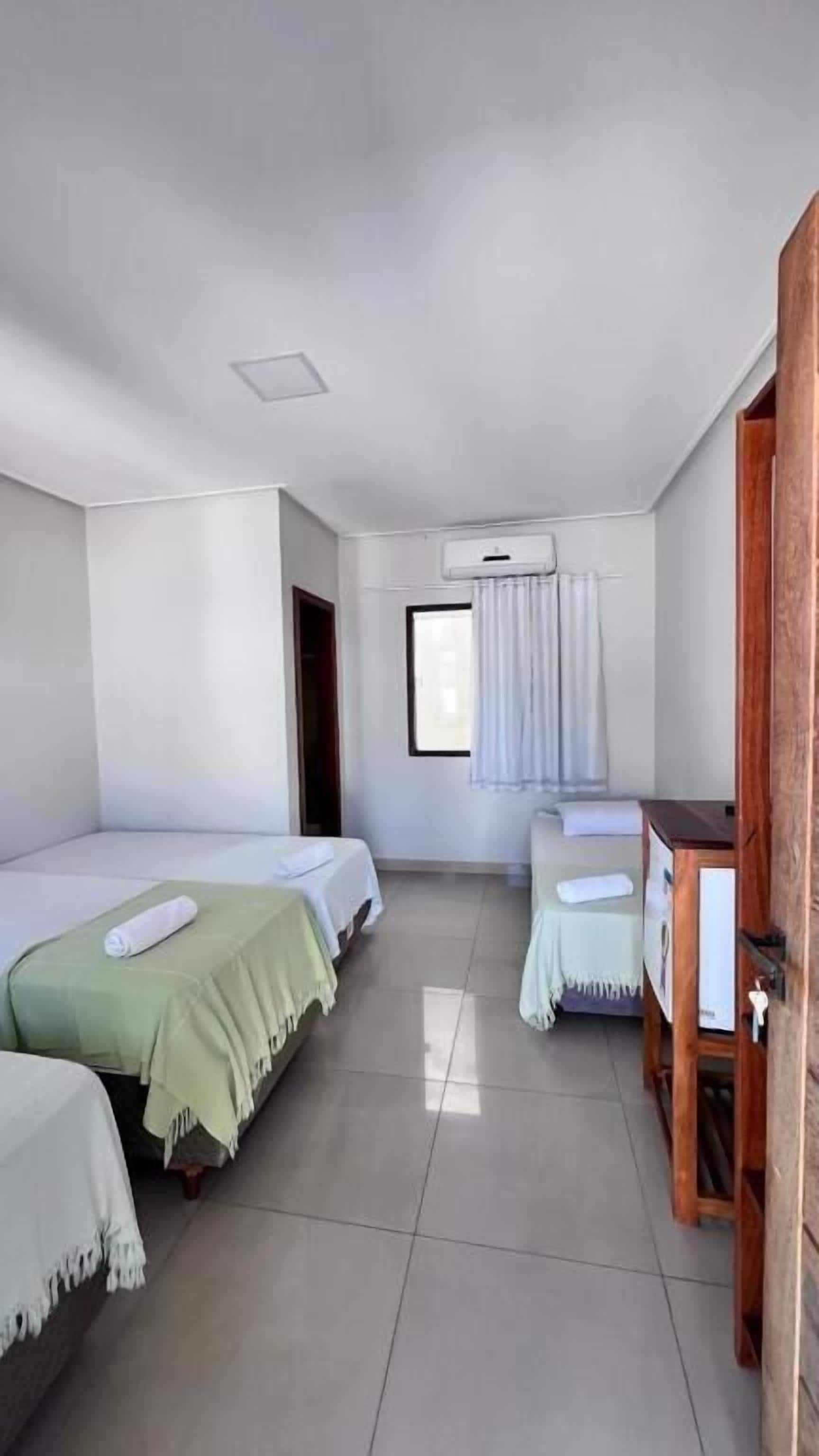 A hotel room with two beds, a wooden desk, and a window with curtains.