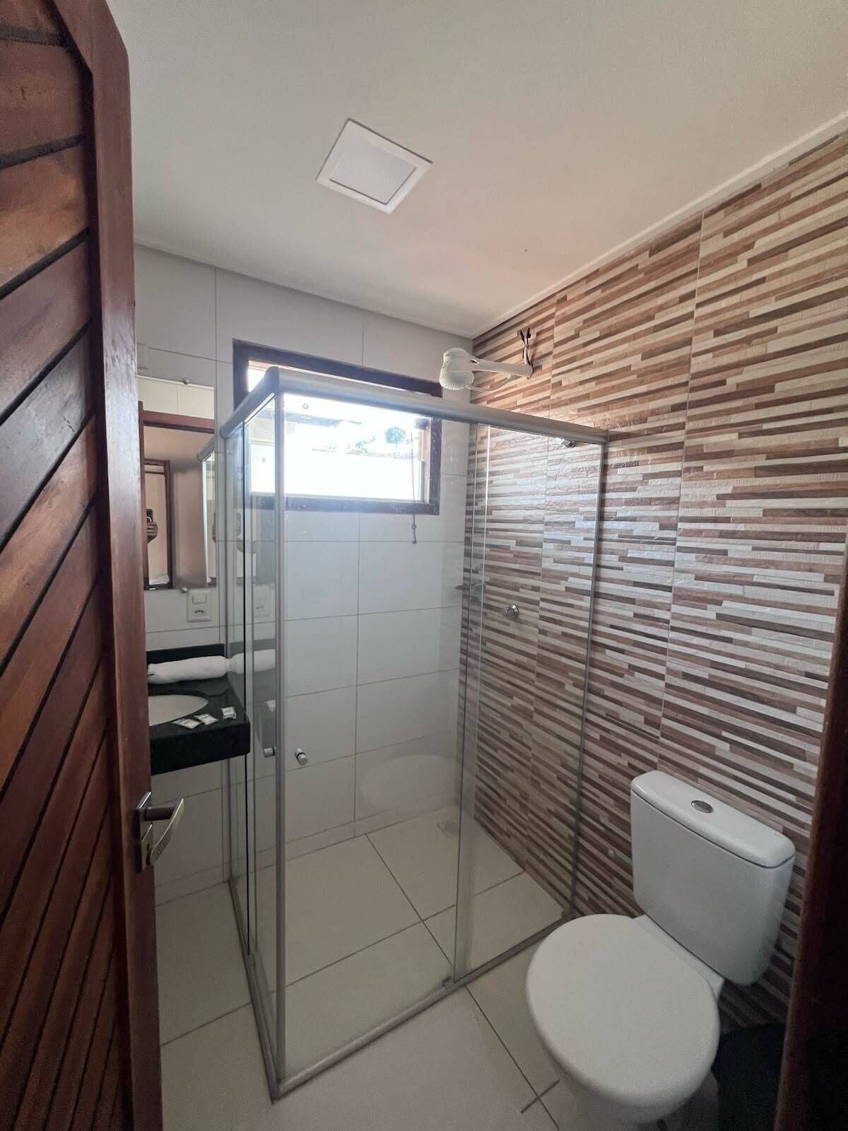 A modern bathroom with a glass shower enclosure, a toilet, and a vanity with a mirror.