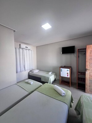 Een hotelkamer met twee eenpersoonsbedden, een klein bureau met een computer, een aan de muur bevestigde televisie en een houten garderobe.