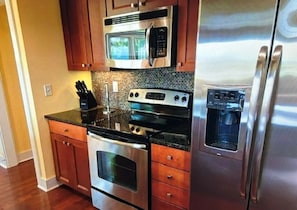 A kitchen with stainless steel appliances, wooden cabinets, and a granite countertop.