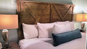 Een bed met een houten hoofdbord, twee kussens en nachtlampjes.