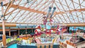 Een overdekt waterpark met glijbanen, een speelruimte en een ruime open ruimte met een hoge plafond.