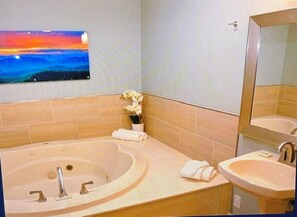 Ein Badezimmer mit einer großen Badewanne, einem Waschbecken und einem Spiegel.