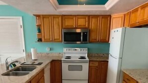 A kitchen with wooden cabinets, a microwave, a stove, and a refrigerator. - Rooftop Oceanview Condo on the Beach Sand w/ Pool! (North Redington Beach)