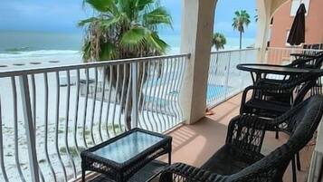 A balcony with a view of the ocean, furnished with a table and chairs.