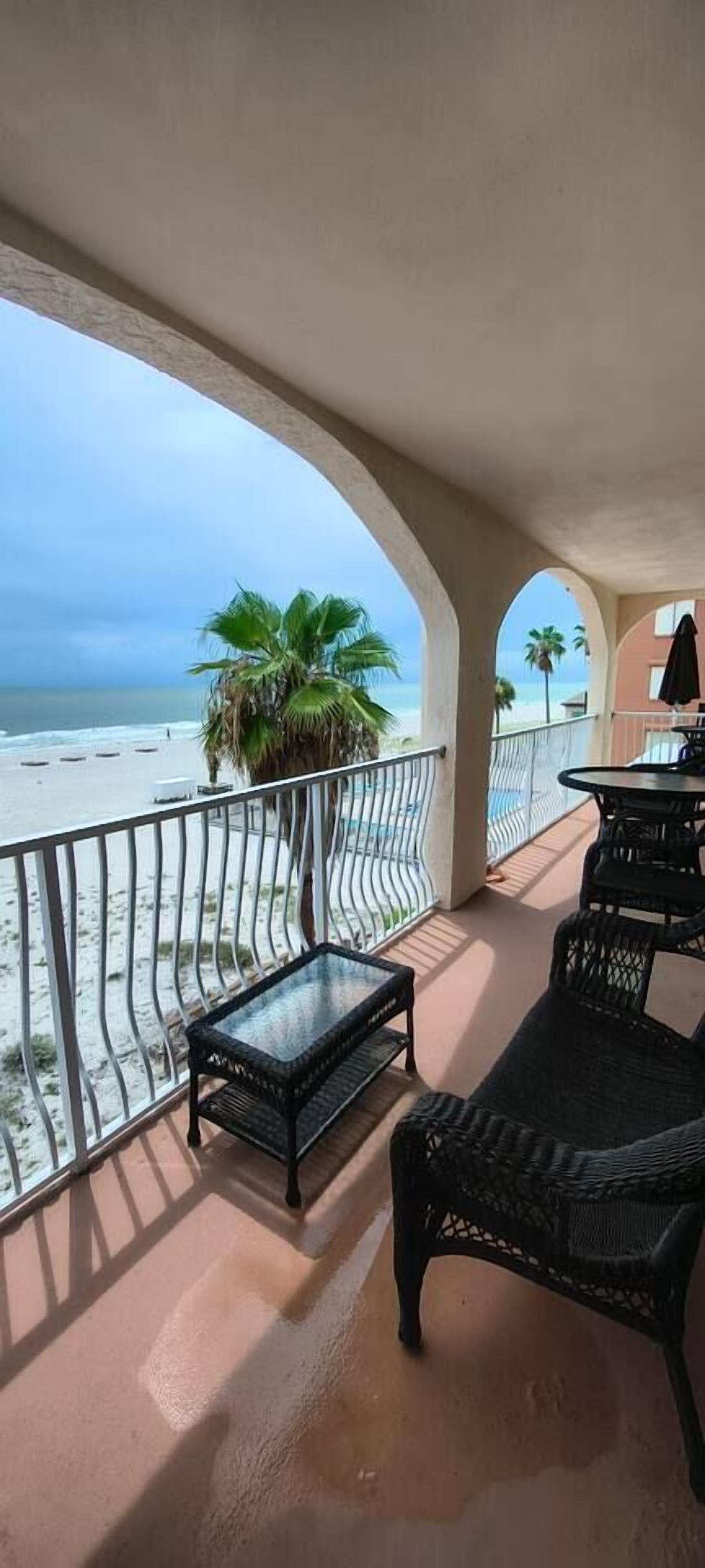Un balcon donnant sur la plage, aménagé avec des meubles en osier et une table.