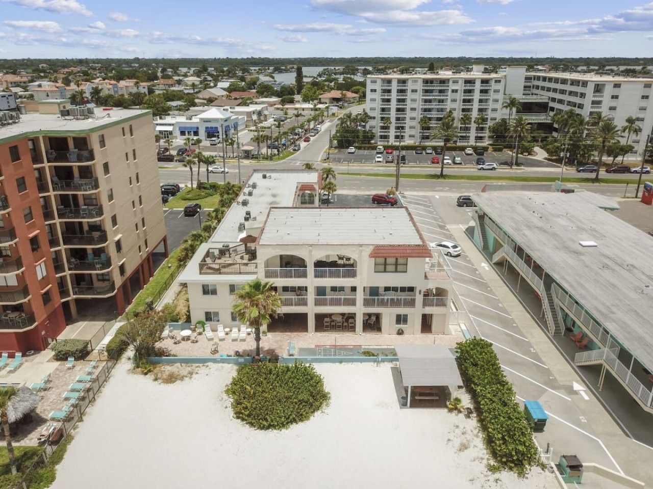 A multi-story hotel with a central courtyard, outdoor seating, and a parking lot.