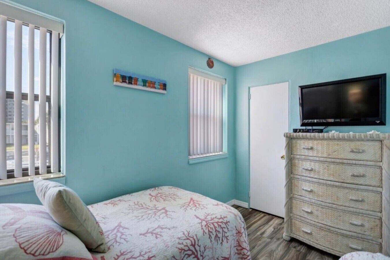 A bedroom with a bed, a dresser, a television, and a window with blinds.