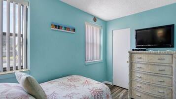 A bedroom with a bed, a dresser, a television, and a window with blinds.