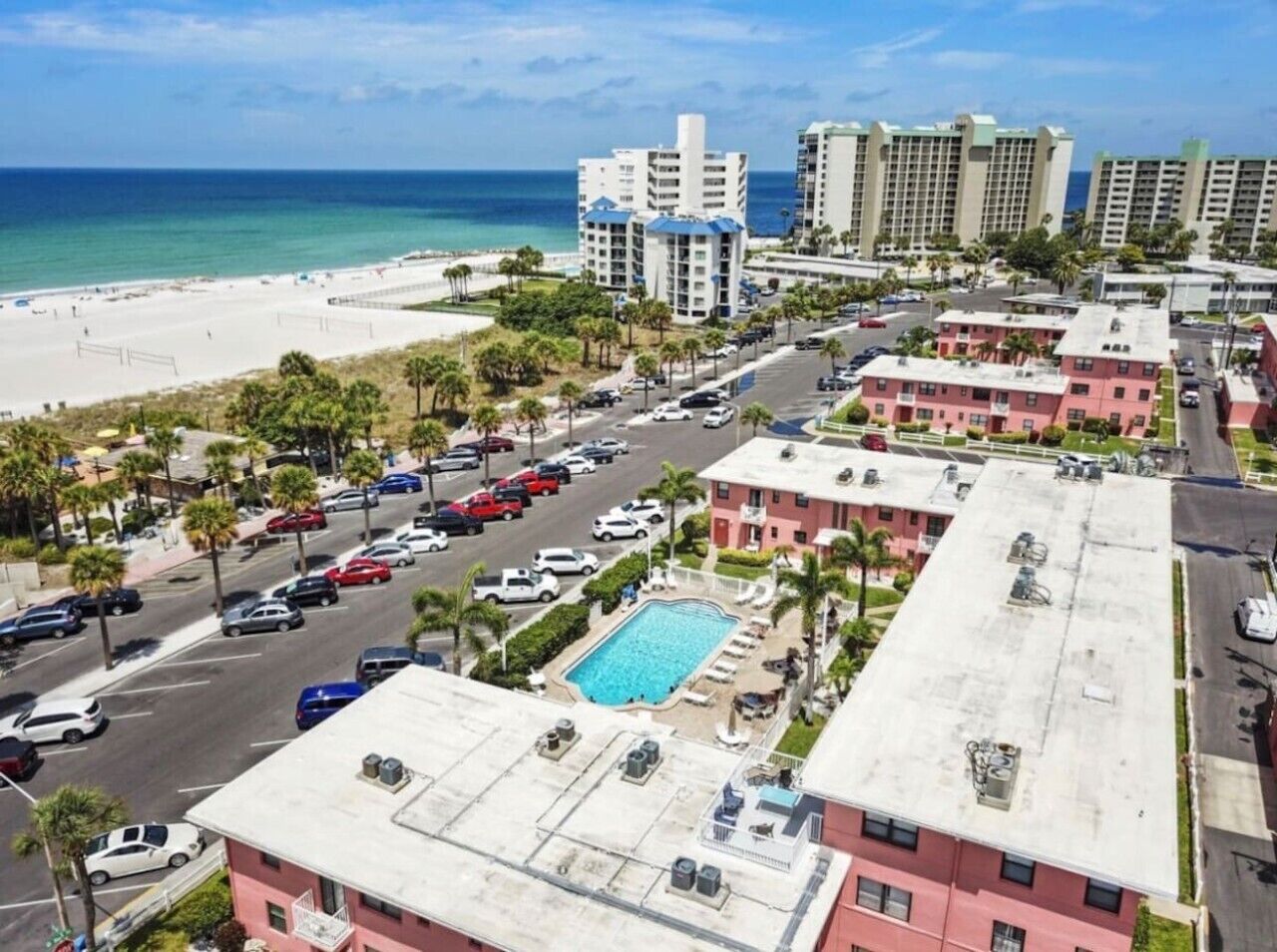 Hotel aan het strand met zwembad, parkeerplaats en uitzicht op de oceaan.