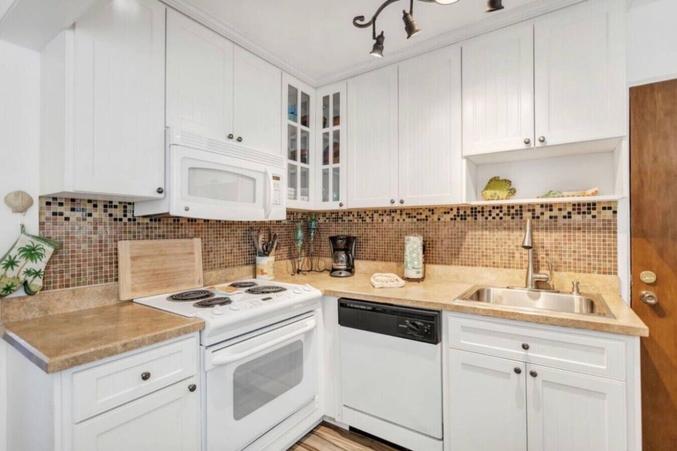 A kitchen with white cabinets, a microwave, a stove, a dishwasher, and a tiled backsplash.