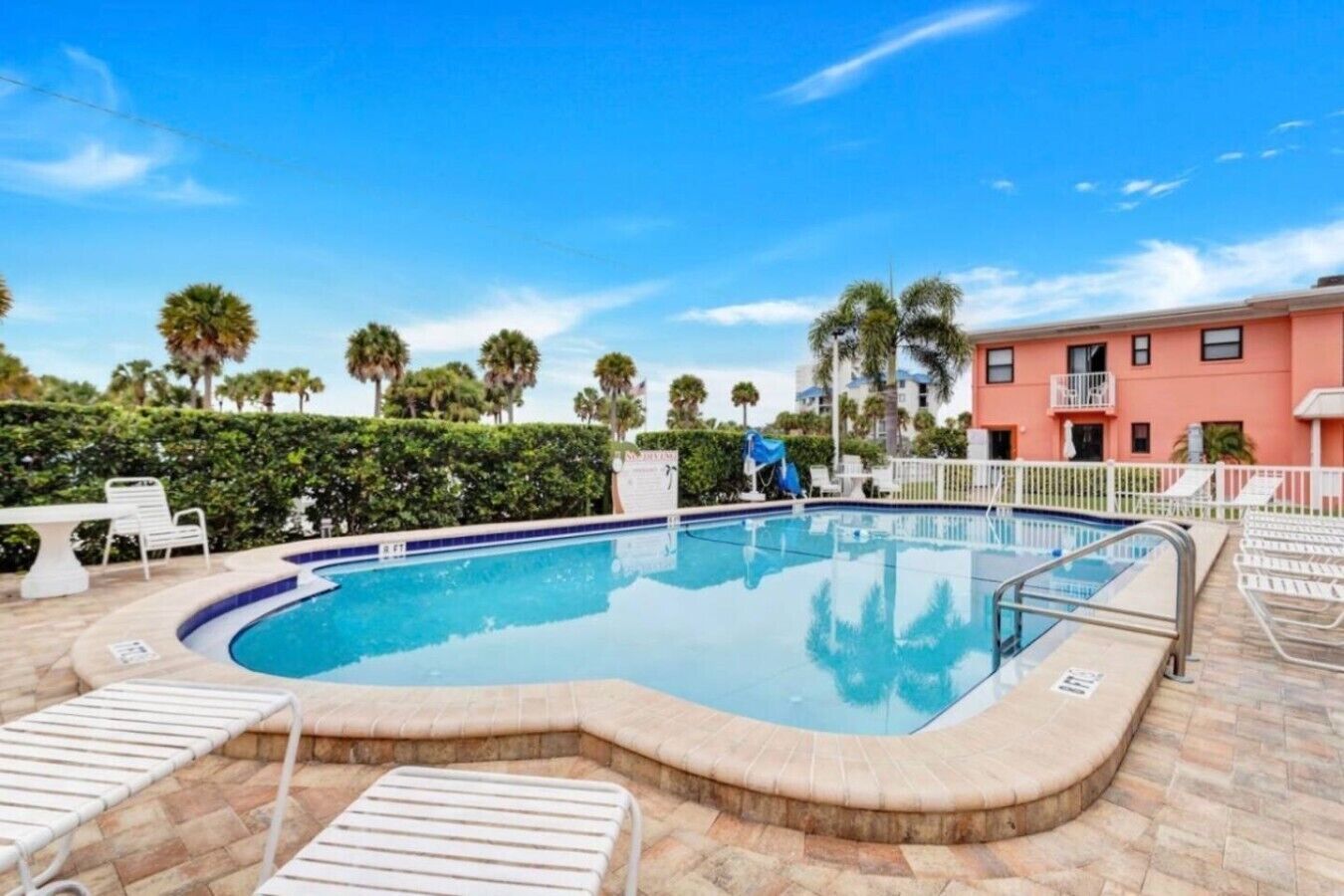 A swimming pool with lounge chairs and a building in the background.