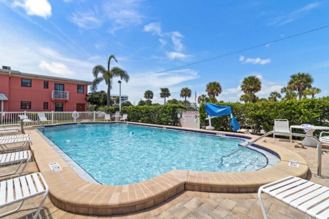 A swimming pool with lounge chairs and a sign indicating diving.