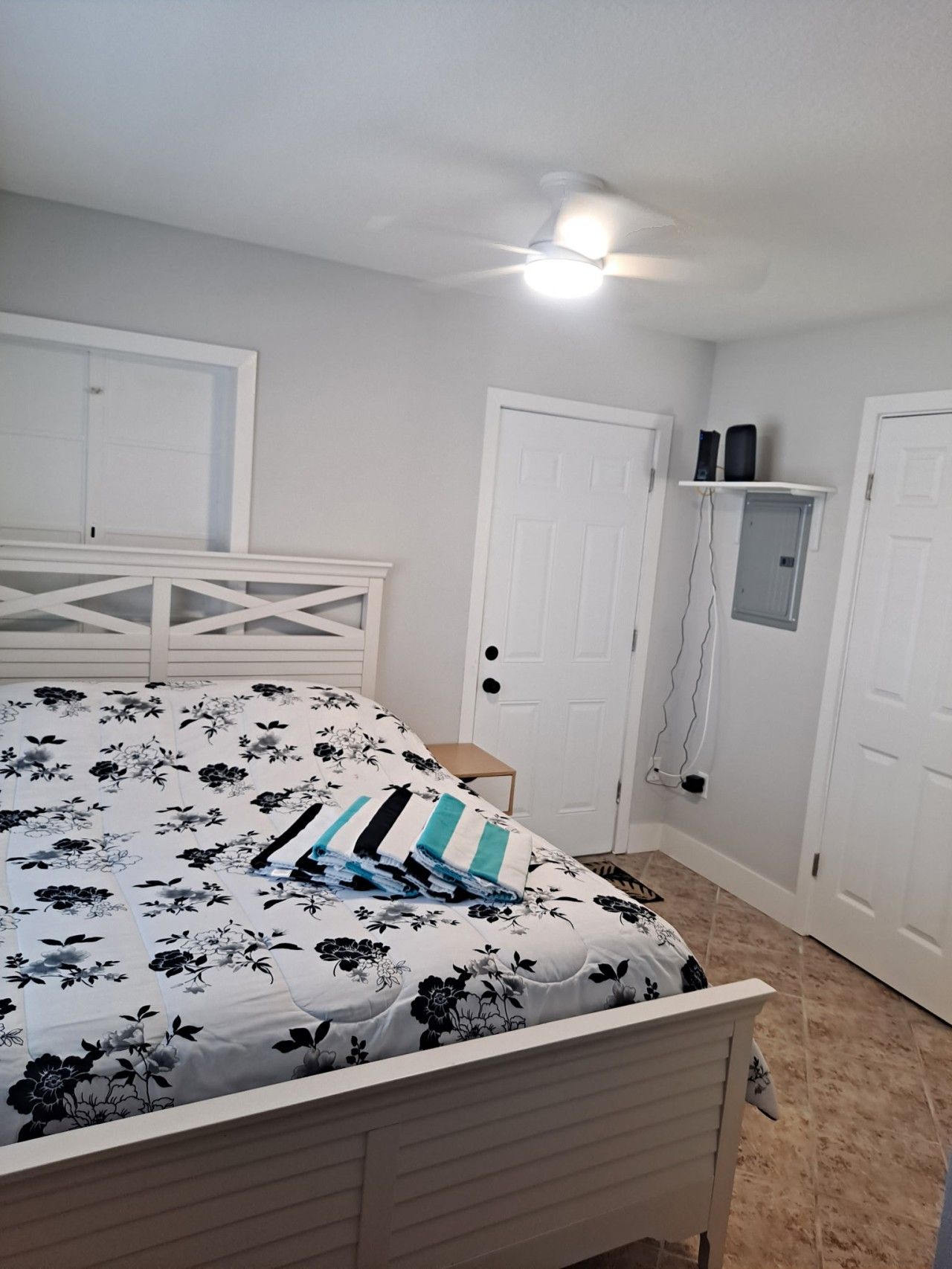 A bedroom with a bed, a ceiling fan, and a white door.