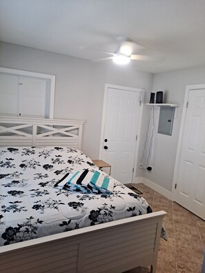Un dormitorio con cama, ventilador de techo y puerta blanca.