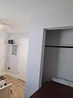 A bedroom with a bed, a white door, and a shelf with items. - Oceanviews w/ Pool & Walk to John’s Pass! (Madeira Beach)