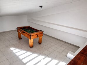Ein Zimmer mit Tischfußball, weißen Wänden und einer geneigten Decke.